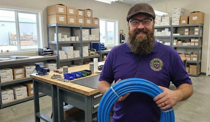 Solo sales company technician holding a large blue coil of industrial hose