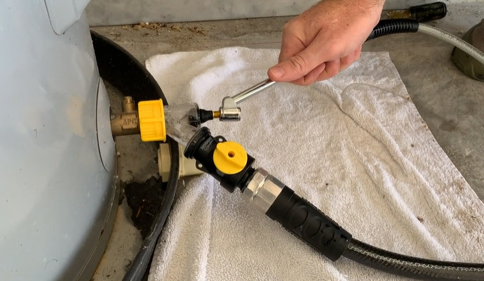 Sediment buster valve attached to a water heater being used with a wrench